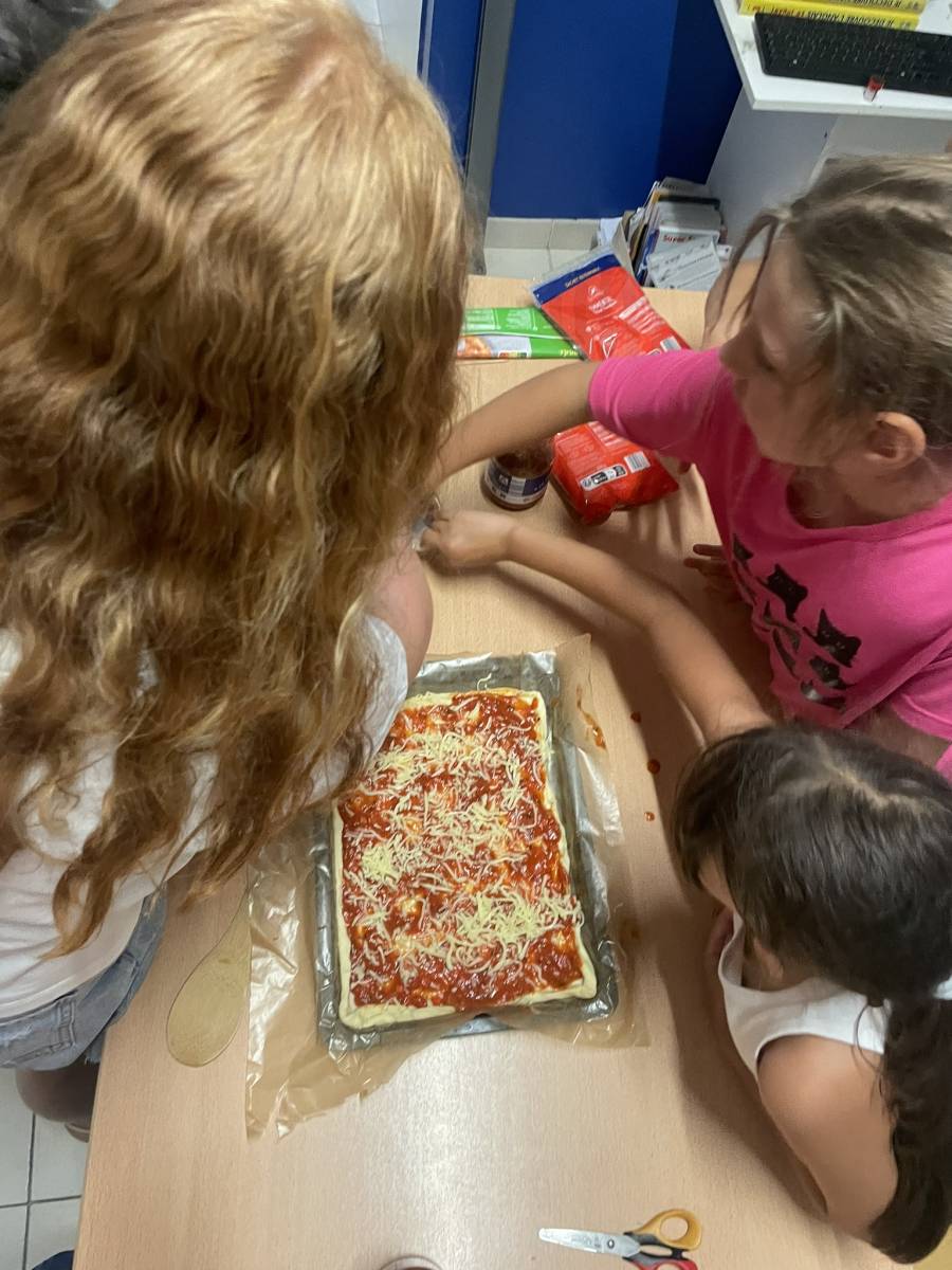 Des enfants souriants participent à un atelier de cuisine créatif lors d'un stage d'anglais immersif à Marseille 13012, encadrés par un professeur anglophone.